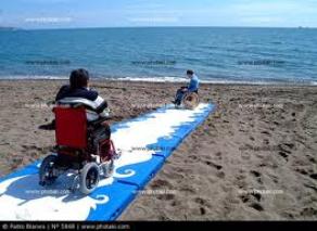 נכה בכיסא גלגלים על שביל גישה בחוף הים