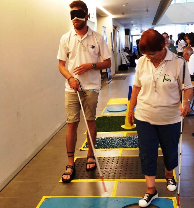 Students attempting to pass through an obstacle course while wearing a blindfold and using a walking stick