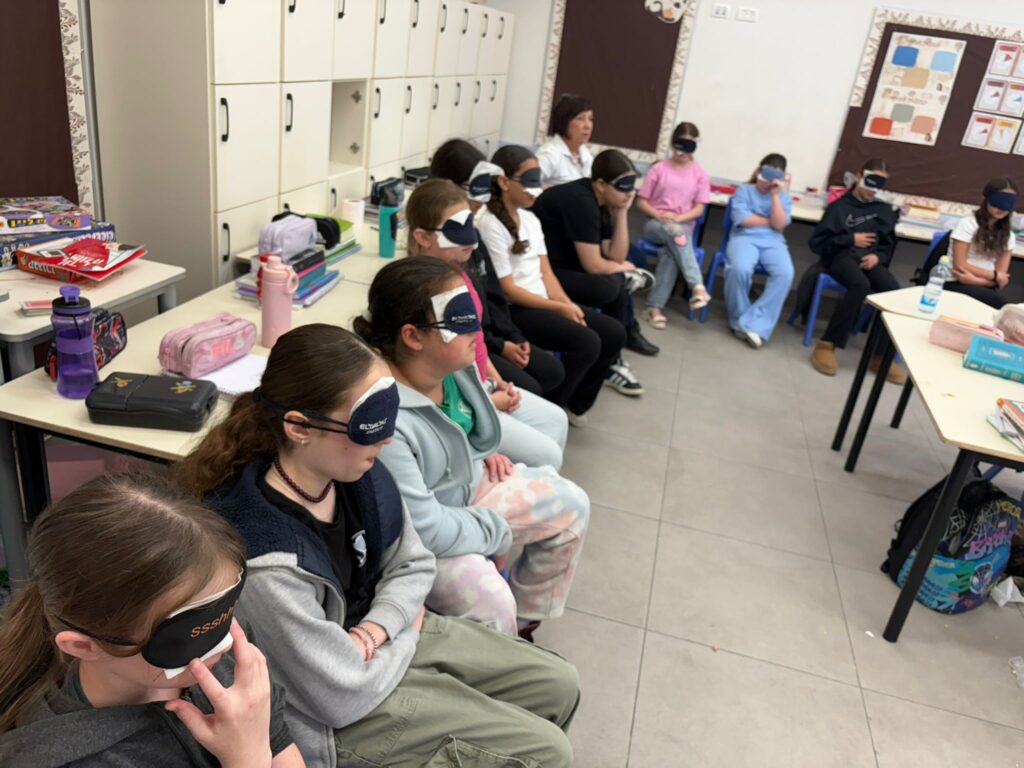 הילדים מתנסים בחבישת סיכוי עניים המדמה מוגבלות בראייה